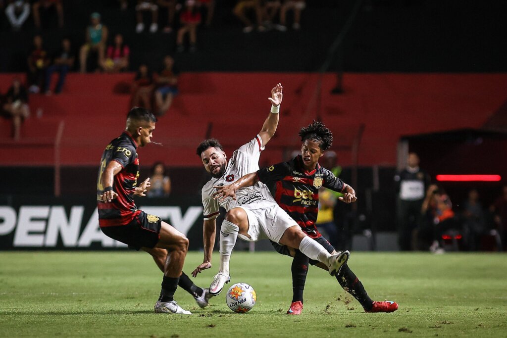partida de futebol, três jogadores disputando a bola