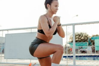a woman doing squats in front of a pool